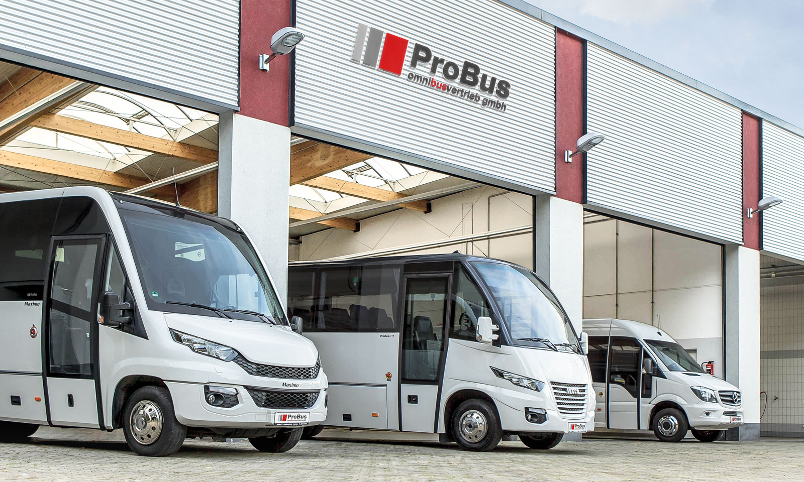 Drei weiße Minibusse von ProBus Omnibusvertrieb vor der Firmenhalle mit Logo über dem Tor